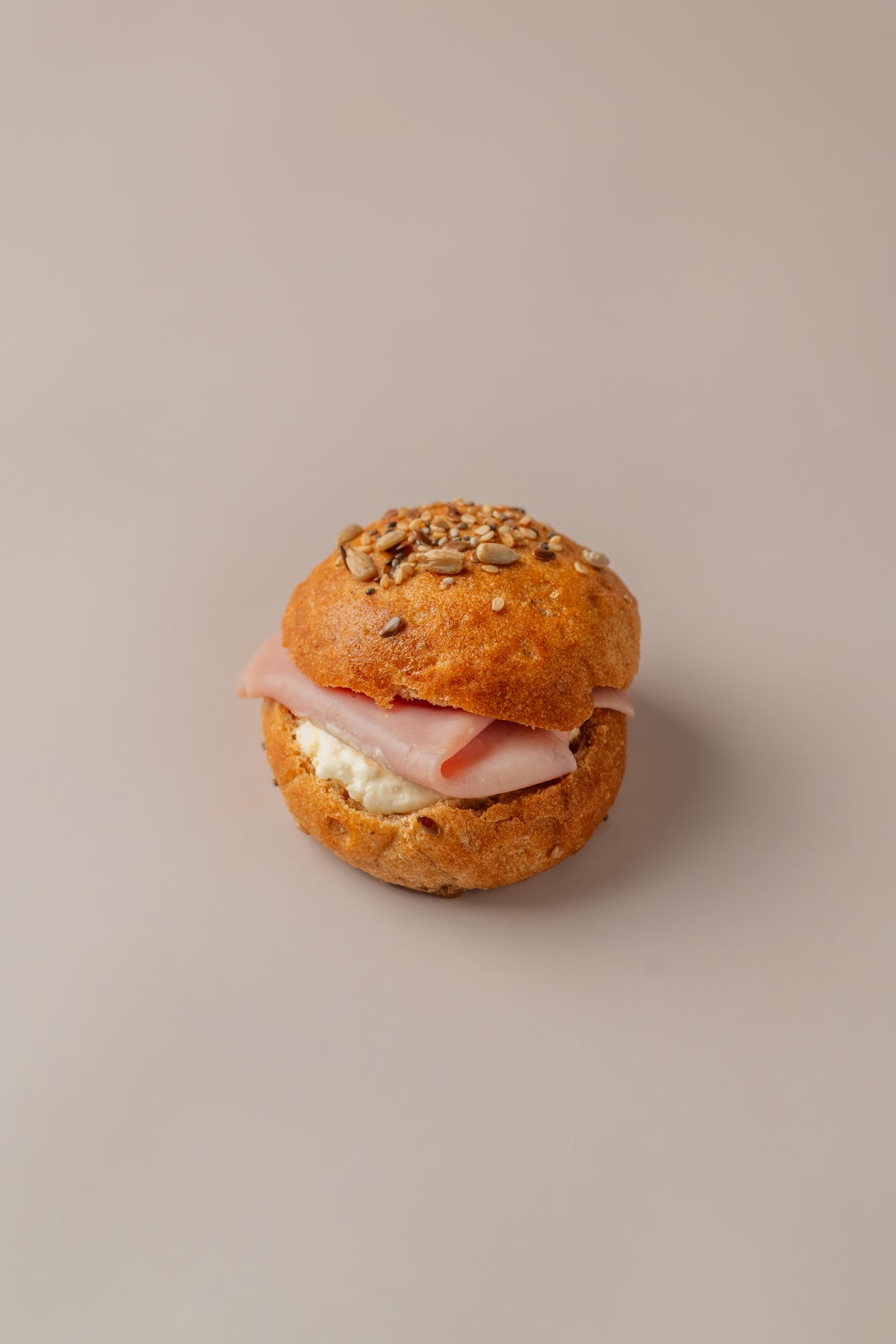 Brioche sin gluten relleno de huevo, mahonesa y jamón york, con pan dorado y semillas.