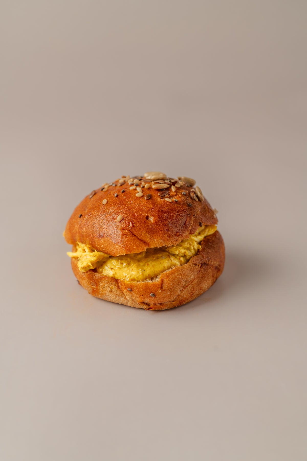 Brioche sin gluten relleno de pollo al curry cremoso, con pan dorado y semillas.