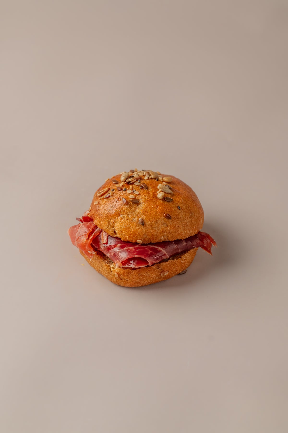 Brioche serranito sin gluten relleno de jamón serrano, con pan brioche dorado y semillas.