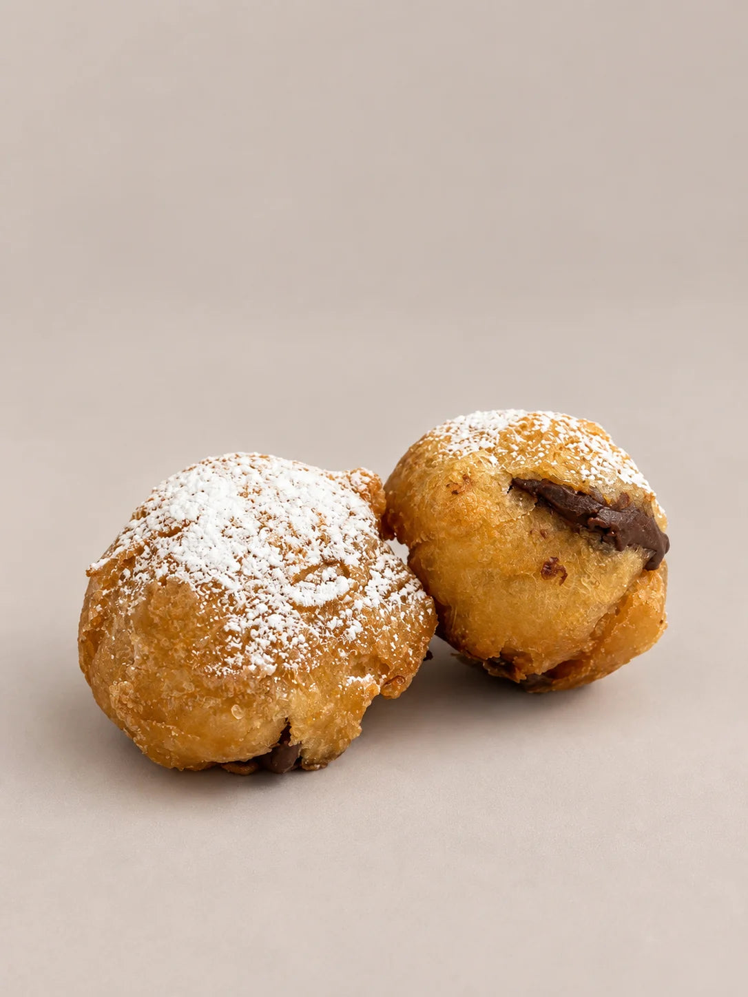 Buñuelos de chocolate sin gluten y sin lactosa, dorados y espolvoreados con azúcar, con relleno de chocolate.
