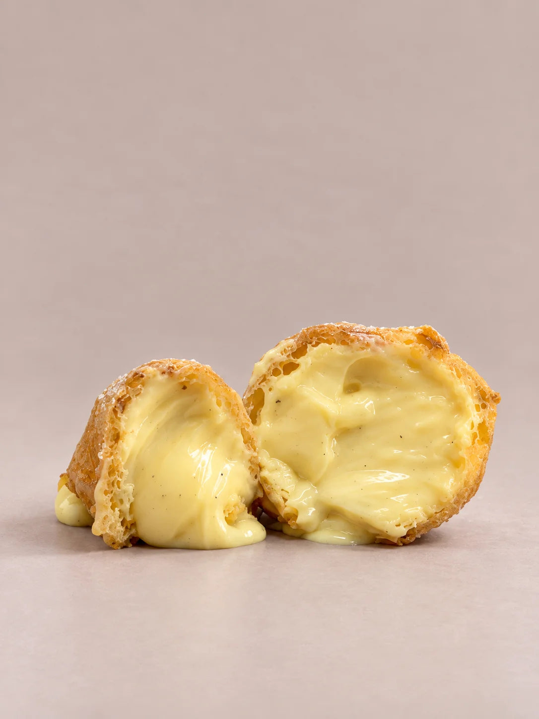 Dos buñuelos de crema de Todos los Santos partidos por la mitad, con masa tierna y crema en su interior, de NICOLINA Madrid.
