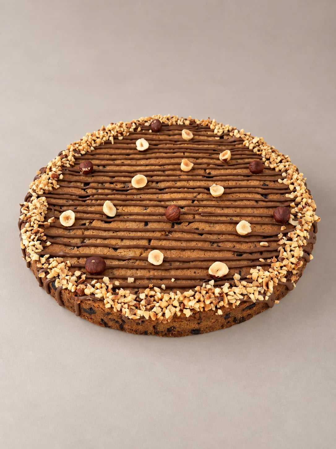 Cookie XXL de chocolate y avellanas sin gluten y sin lactosa de NICOLINA Madrid, vista exterior artesanal con chocolate y avellanas tostadas.
