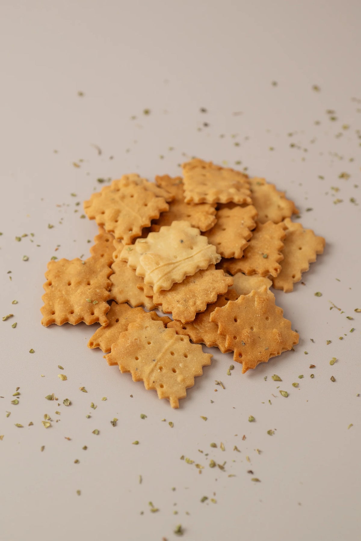 Crackers de orégano sin gluten y sin lactosa servidos con hierbas aromáticas y textura crujiente.
