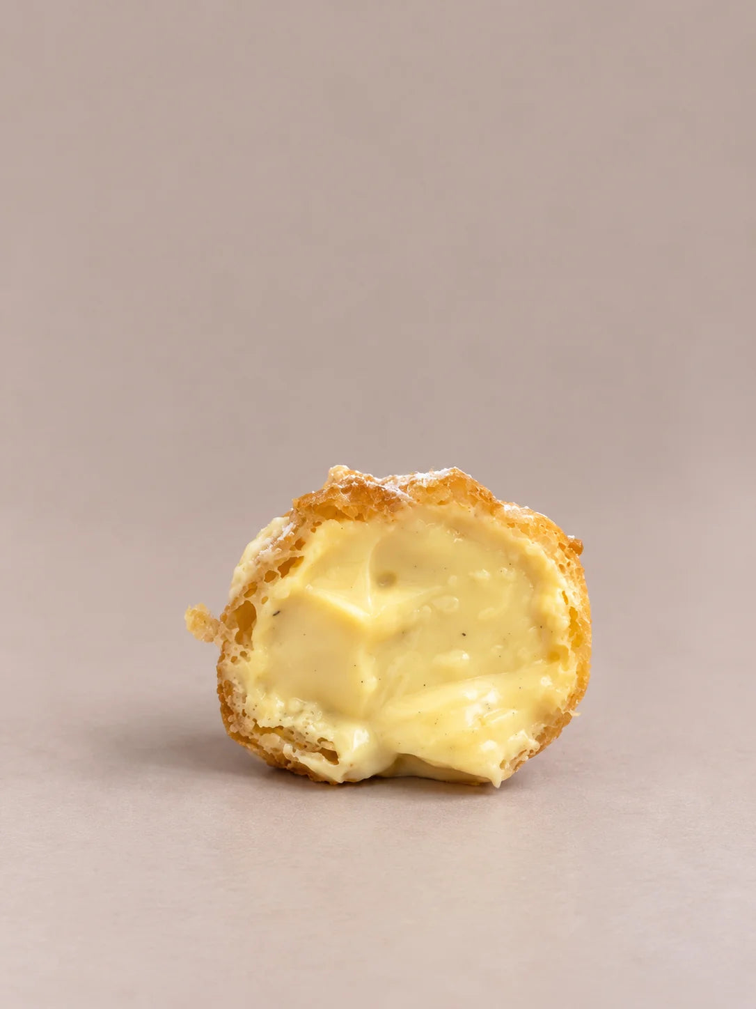 Detalle de un buñuelo de crema artesanal sin gluten, partido y relleno de crema.