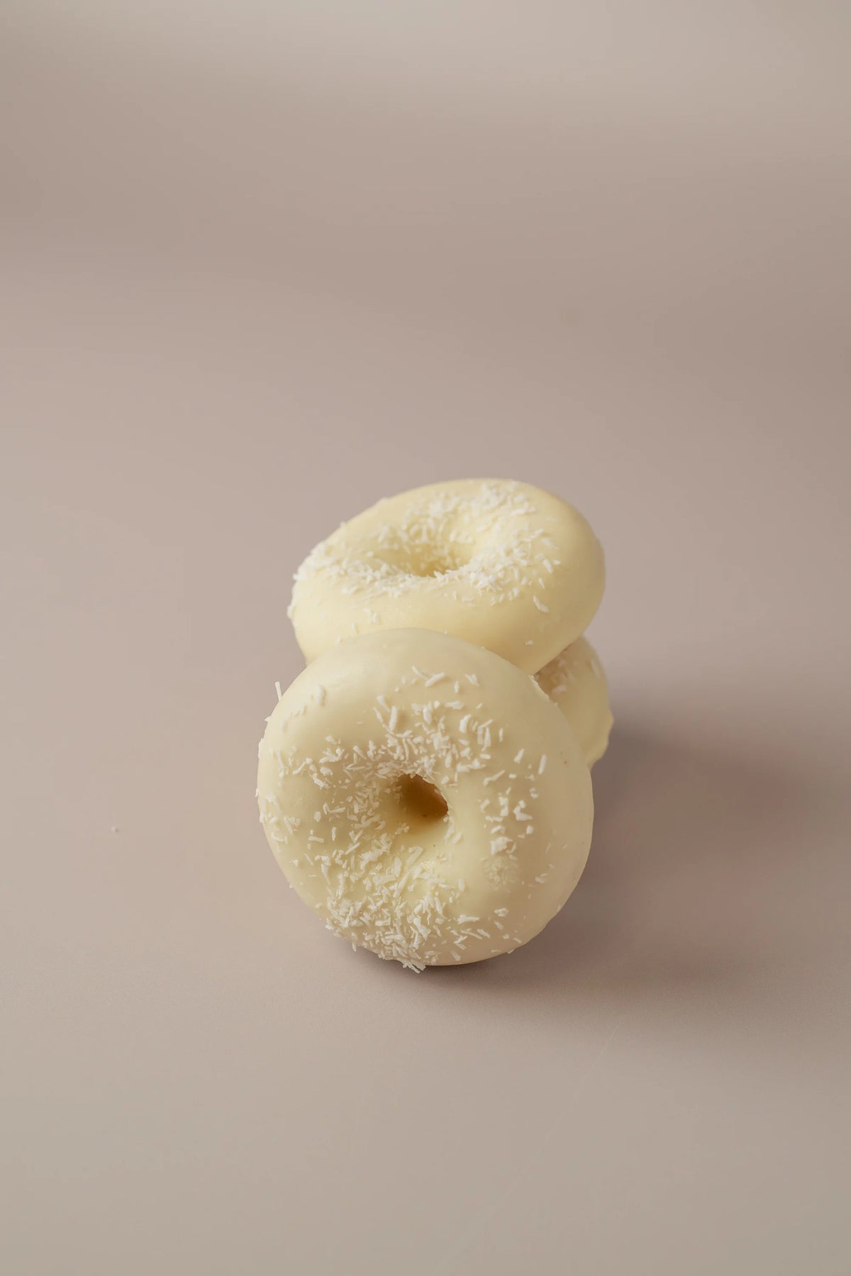 Detalle de donat artesanal de coco con cobertura cremosa de chocolate blanco y coco rallado.