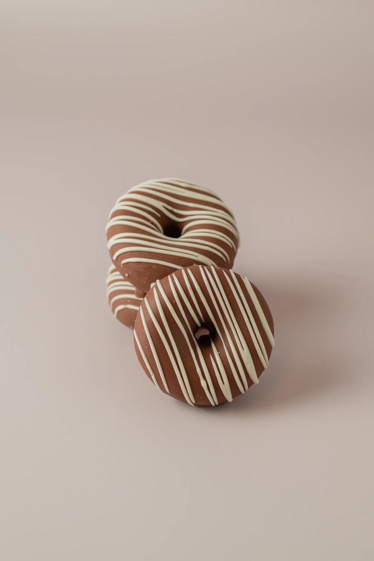 Detalle de donat kinder artesanal sin gluten y sin azúcar con cobertura de chocolate y decoración de chocolate blanco.