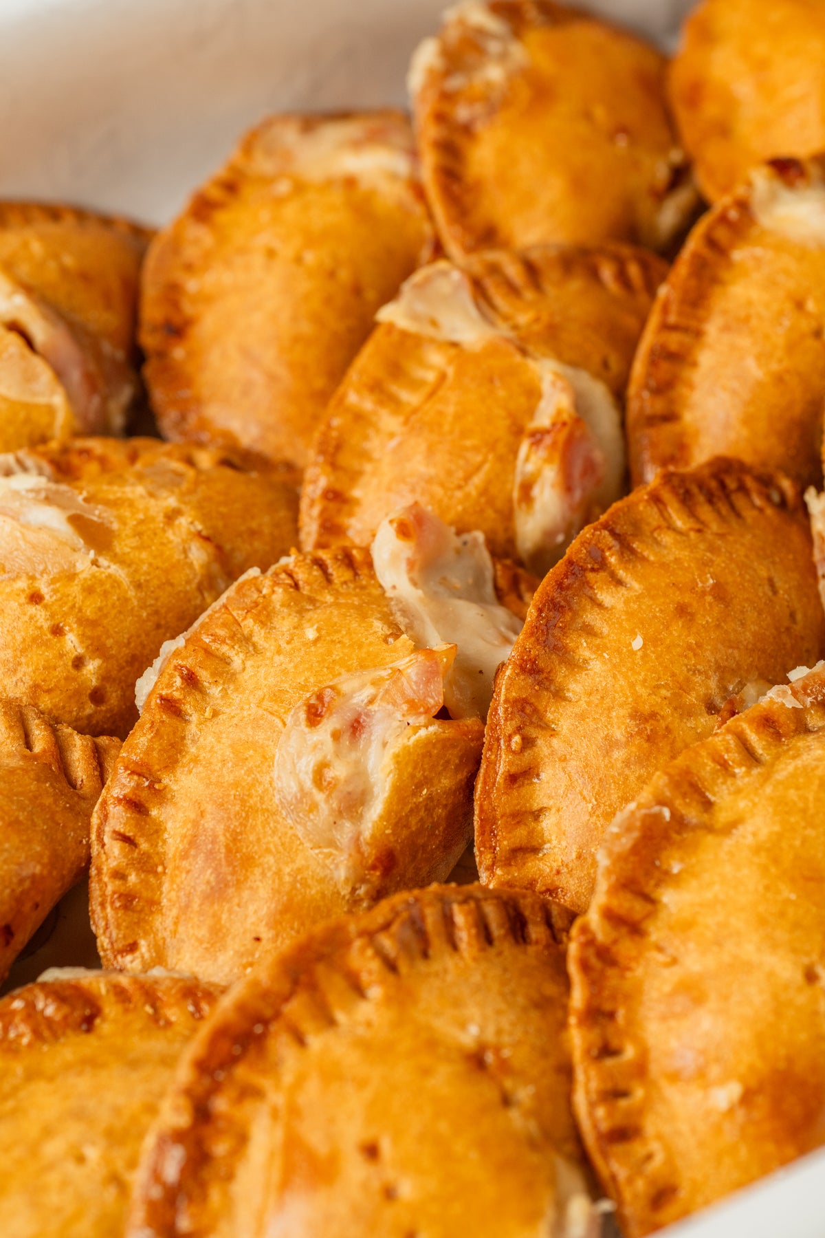 Detalle de mini empanadillas sin gluten doradas, con su borde repulgado, de NICOLINA.
