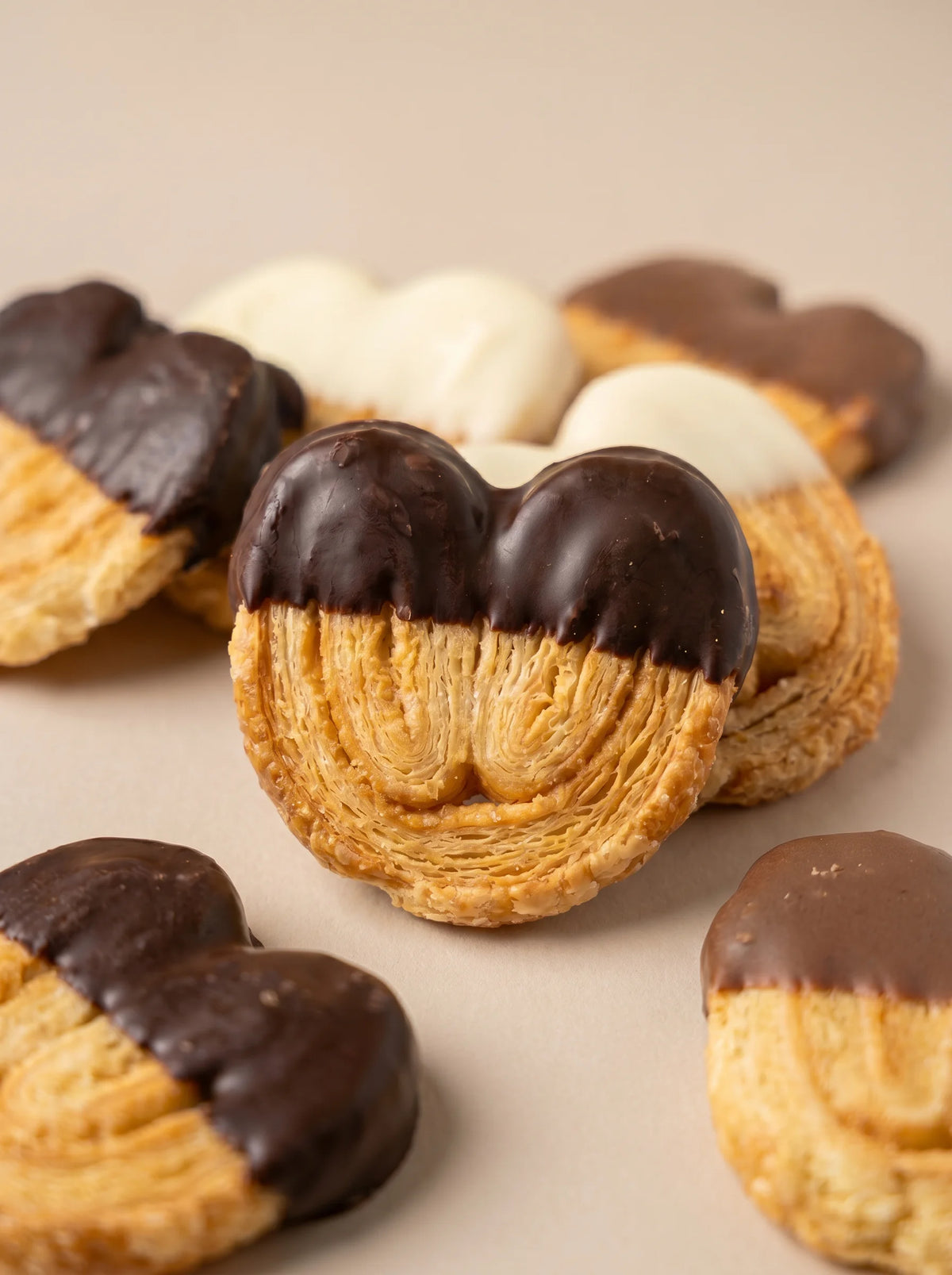 Detalle de palmeritas artesanales sin gluten con capas de hojaldre y baño de chocolate.
