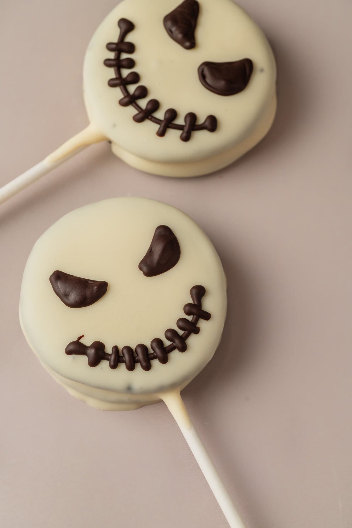 Detalle de dos piruletas Jack sin gluten de NICOLINA, con la cara del personaje sobre cobertura blanca.