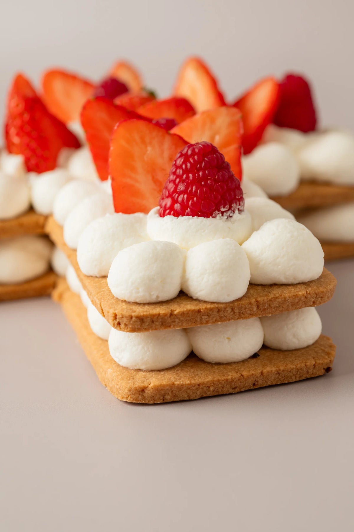 Detalle de tarta artesanal con forma de cruz sin gluten, sin azúcar y sin lactosa decorada con frutos rojos frescos.

