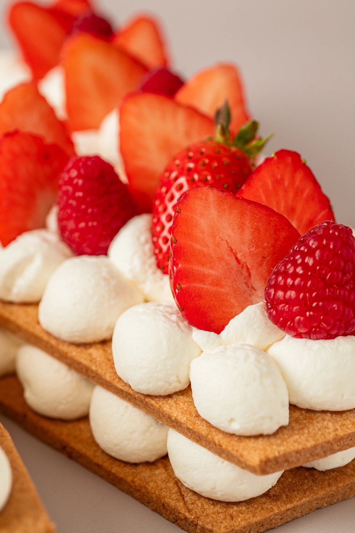 Detalle de tarta letra artesanal sin gluten, sin azúcar y sin lactosa con crema ligera y frutos rojos frescos.
