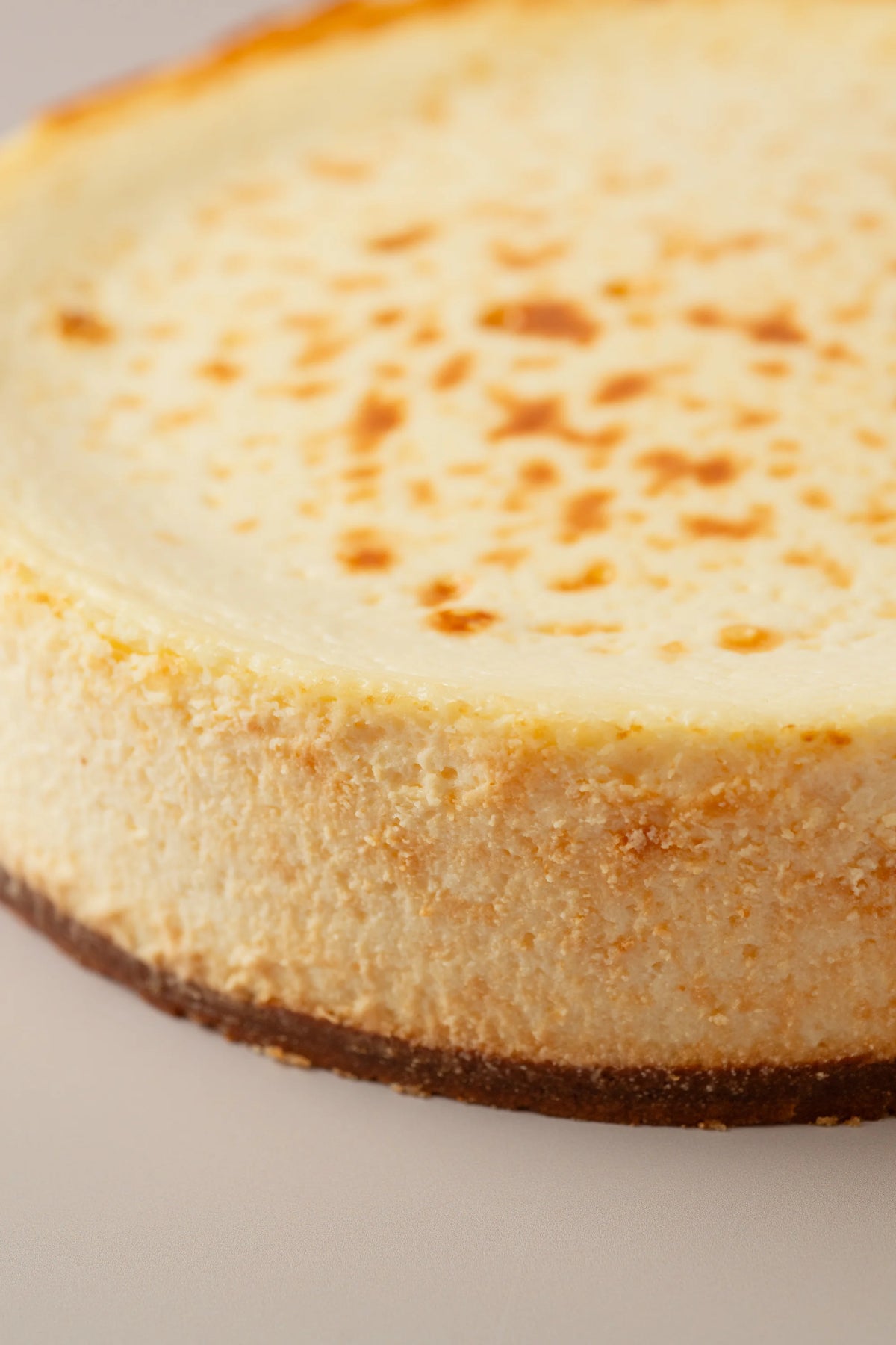 Detalle de tarta de queso cremosa sin gluten de NICOLINA Madrid, con superficie dorada y textura suave artesanal.
