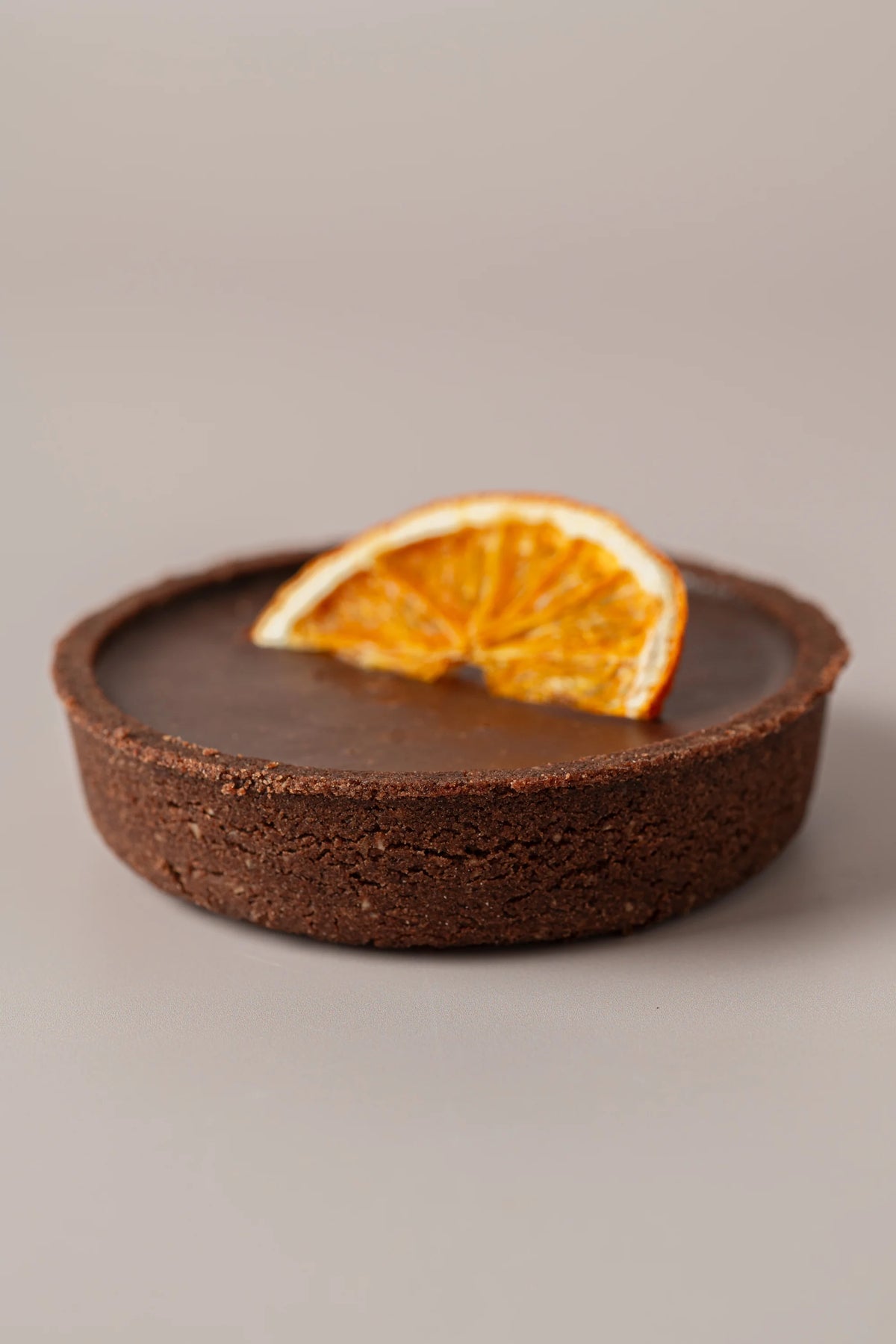 Tartaleta de chocolate y naranja sin gluten, sin lactosa y sin azúcar con base crujiente de cacao y decoración de naranja.
