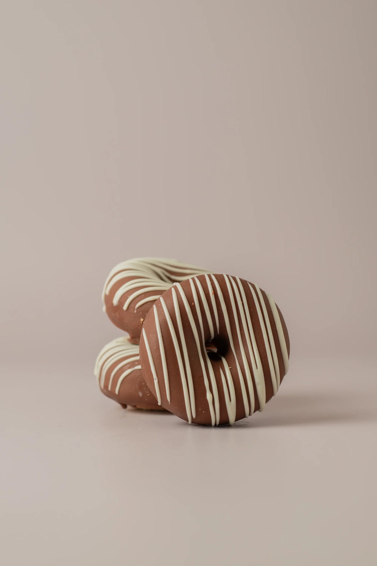 Donat kinder sin gluten y sin azúcar de NICOLINA Madrid con cobertura de chocolate con leche y líneas de chocolate blanco.