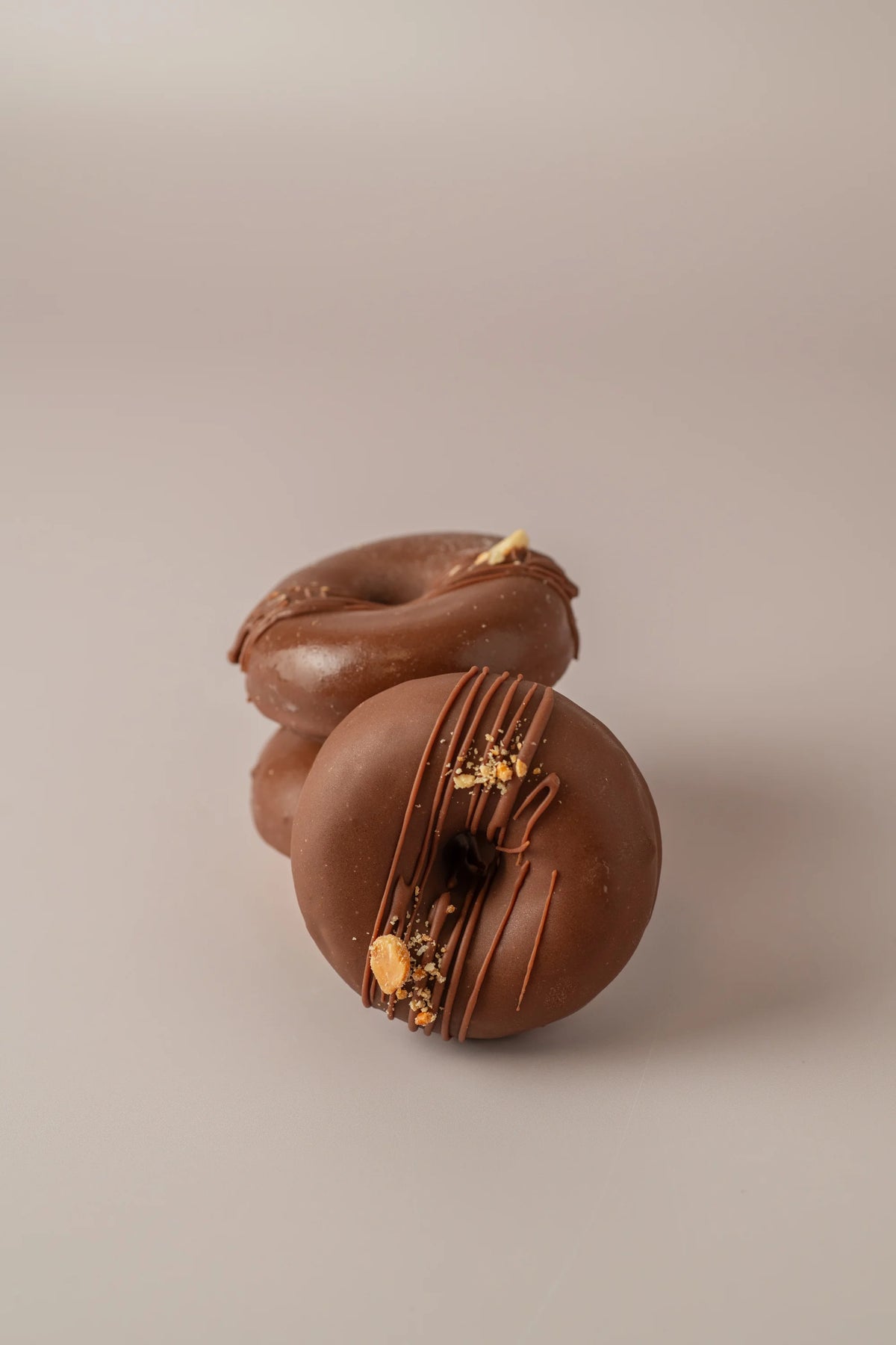 Donat peanut artesanal sin gluten y sin azucar de NICOLINA Madrid con cobertura de chocolate y trozos de cacahuete.