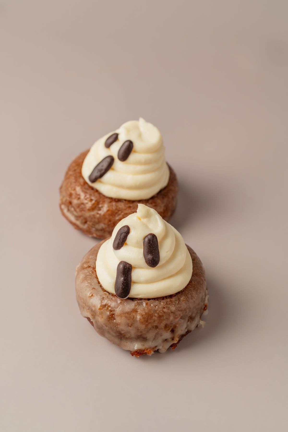 Dos donats carrot cake de Halloween de NICOLINA Madrid, glaseados y coronados con fantasmas de frosting de crema.