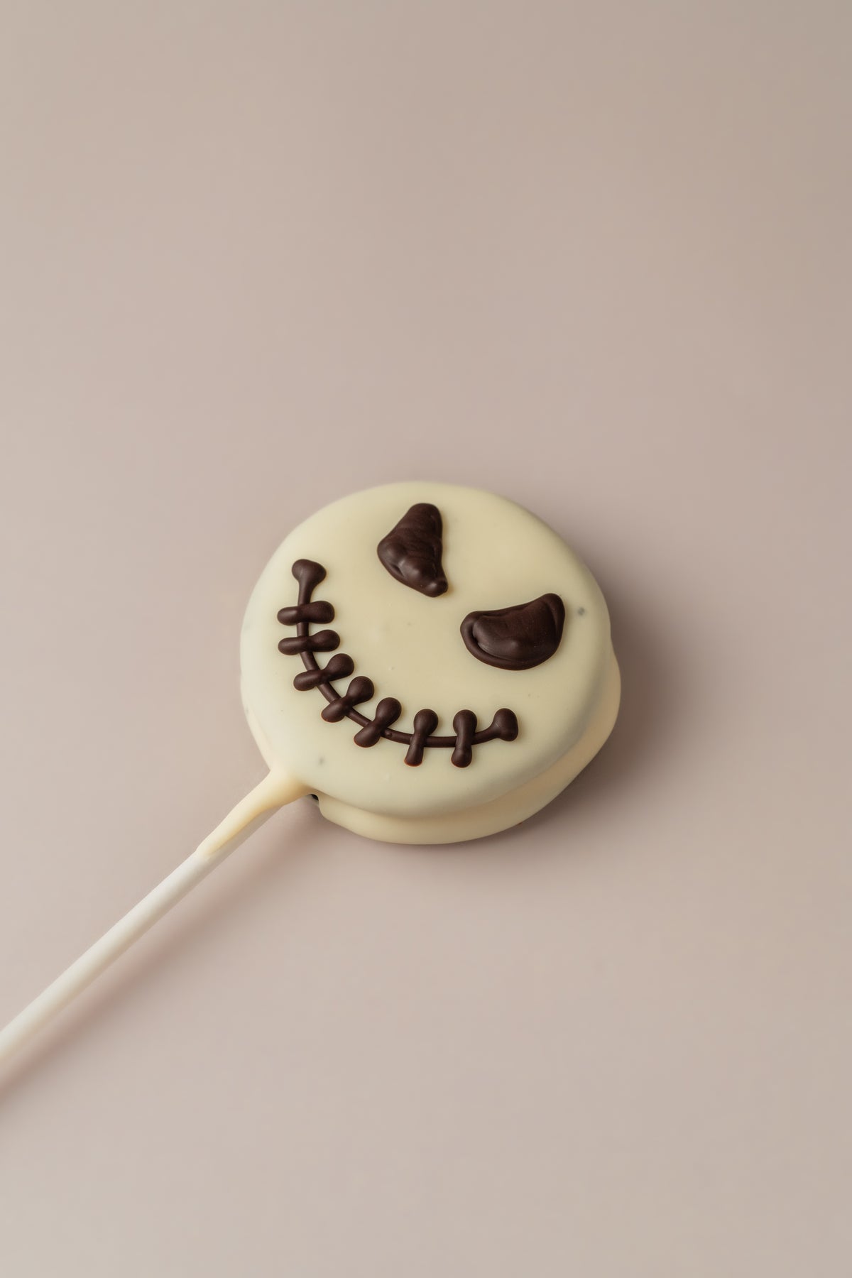 Piruleta Jack de Halloween sin gluten de NICOLINA Madrid, galleta con cobertura blanca y la cara de Jack dibujada a mano.