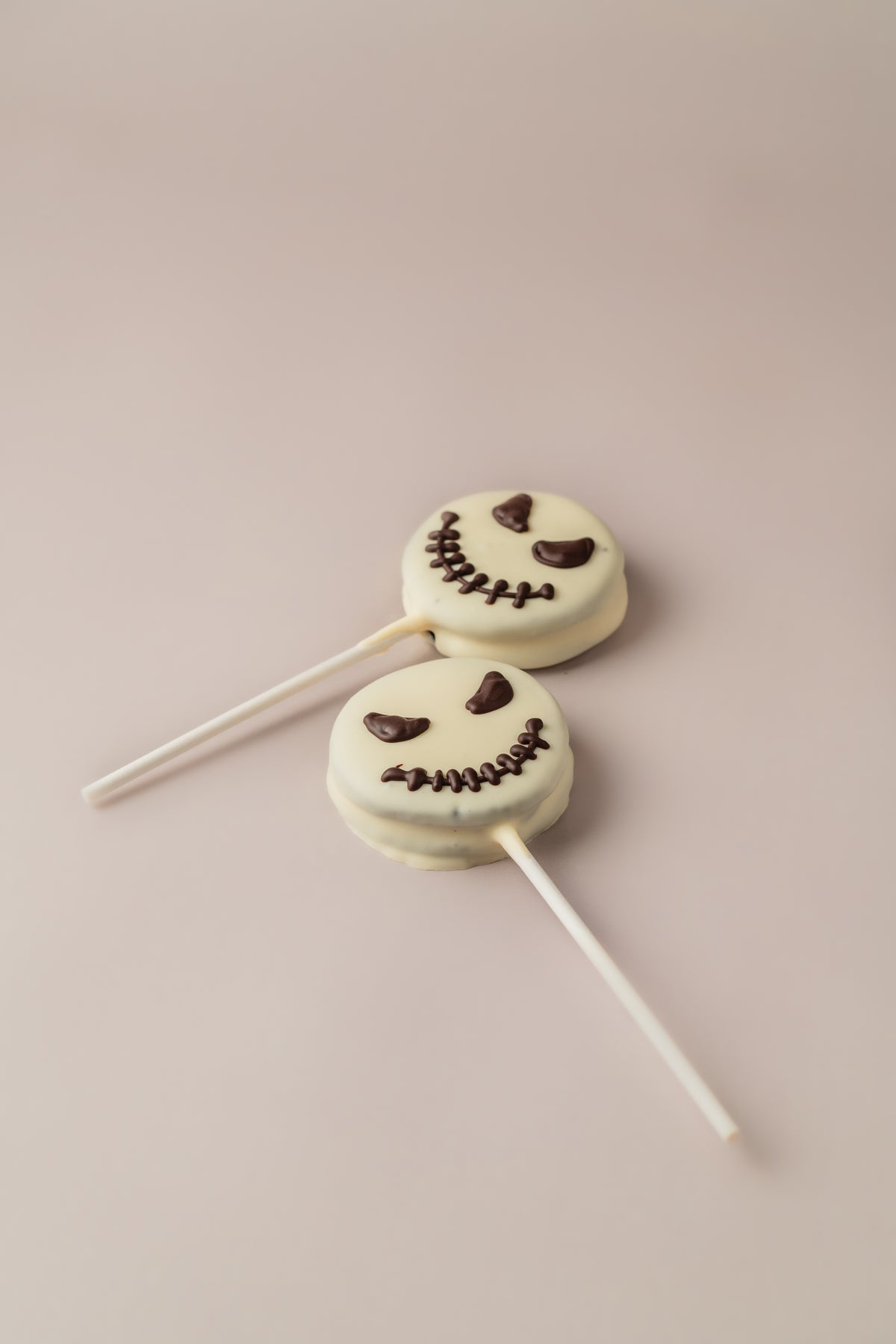 Dos piruletas Jack de Halloween artesanales de NICOLINA Madrid, con ojos y sonrisa cosida dibujados a mano.