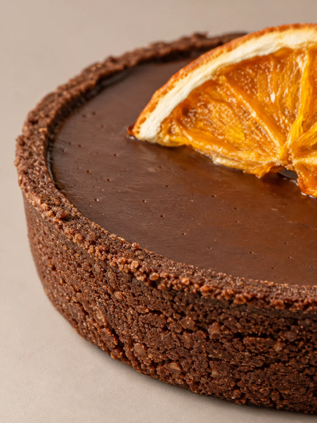 Detalle de tartaleta de chocolate sin gluten, sin lactosa y sin azúcar con base de cacao y toque de naranja natural.
