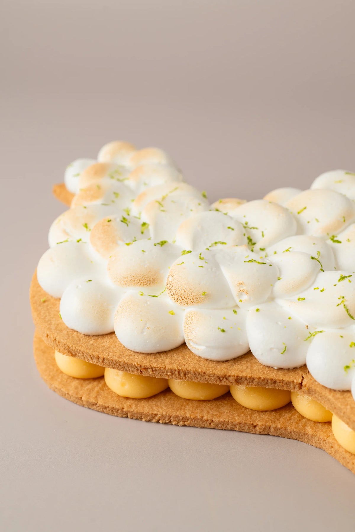 Primer plano de tarta paloma sin gluten, sin azúcar y sin lactosa con base de galleta artesanal, crema de limón y merengue tostado.
