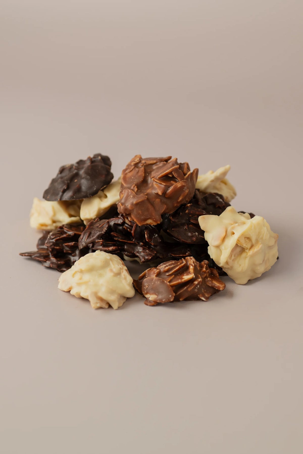 Detalle de rocas de chocolate negro, blanco y con leche sin gluten y sin azúcar con textura crujiente de almendra.
