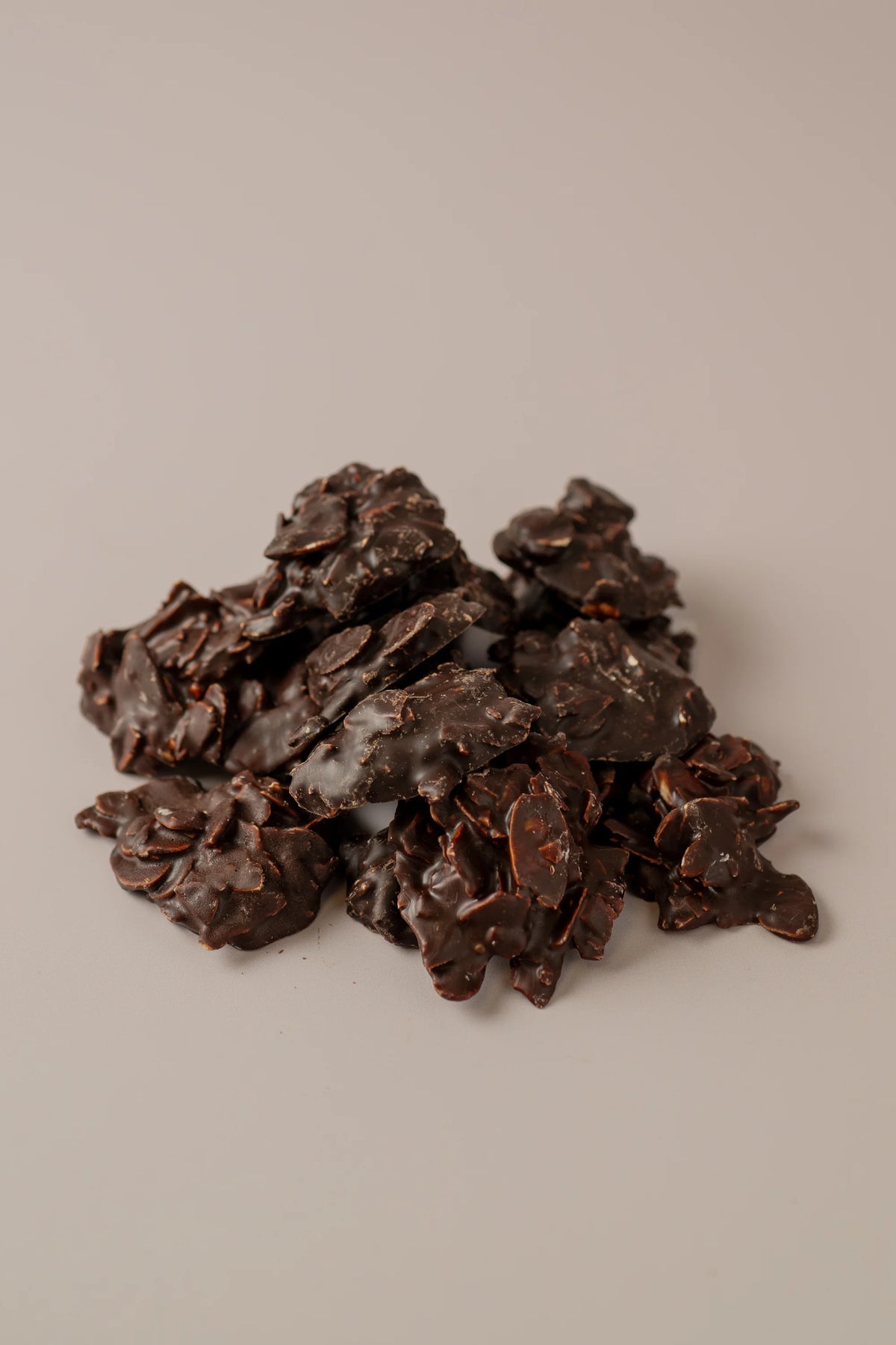 Rocas de chocolate negro con almendras sin gluten y sin azúcar, pequeños bocados intensos de cacao.
