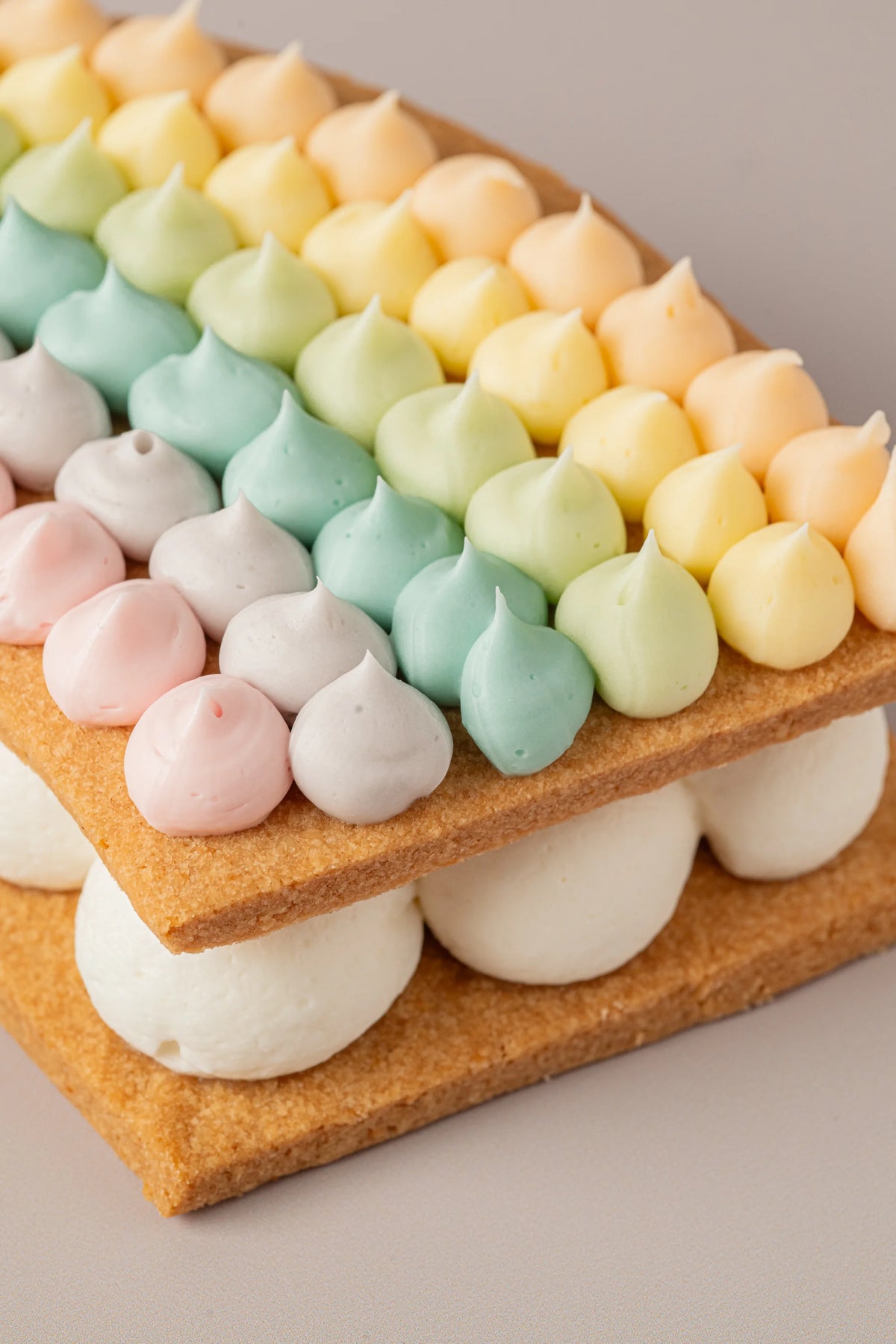 Tarta arcoíris artesanal sin gluten, sin azúcar y sin lactosa con relleno cremoso y galleta crujiente.
