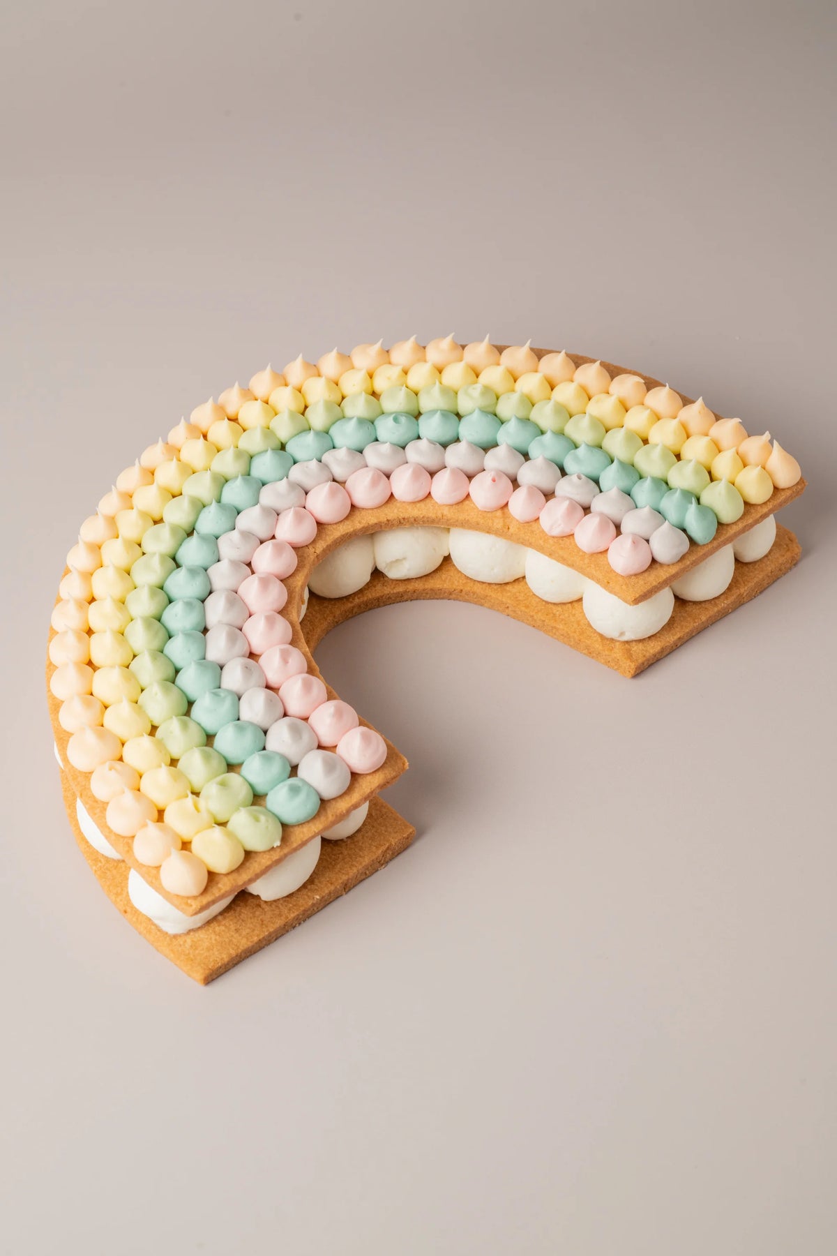 Tarta arcoíris sin gluten, sin azúcar y sin lactosa con decoración pastel y crema suave artesanal.

