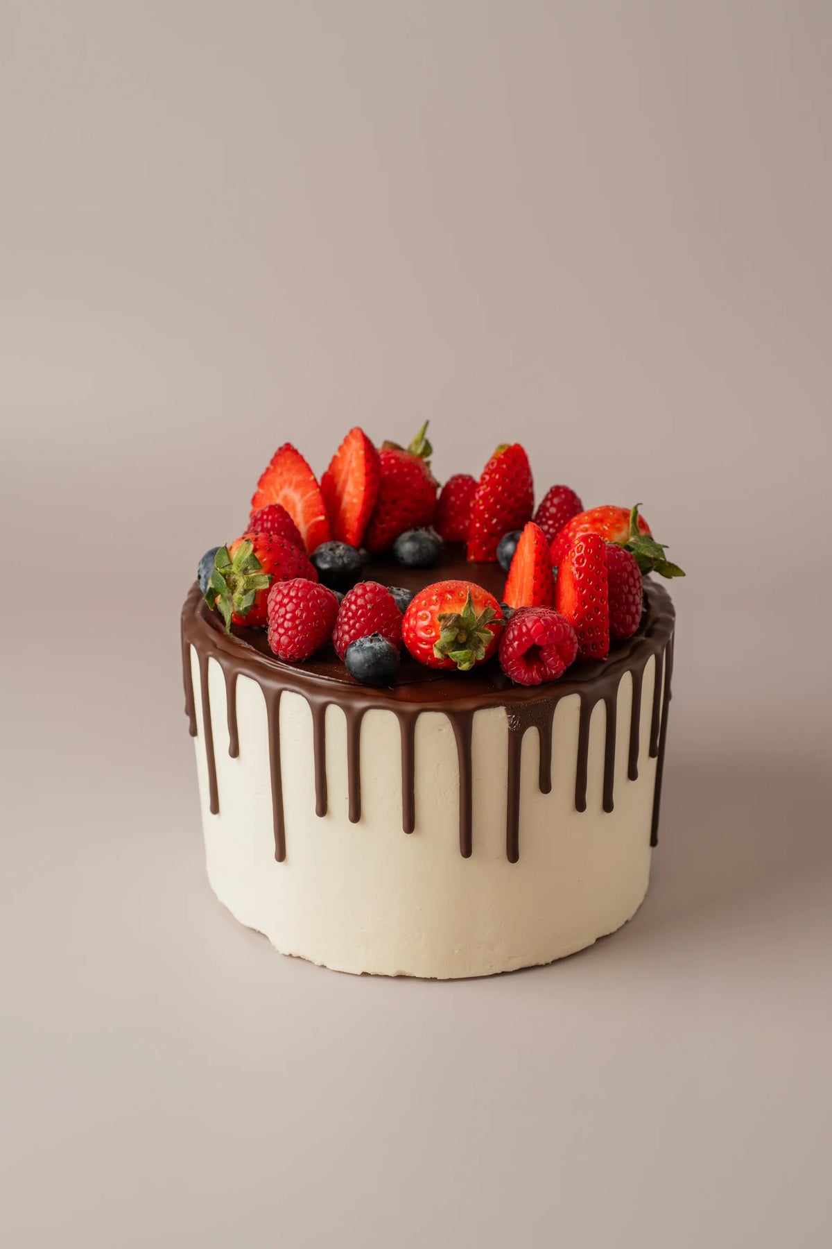 Tarta de cumpleaños de 12 porciones sin gluten y sin azúcar decorada con chocolate y frutos rojos frescos.
