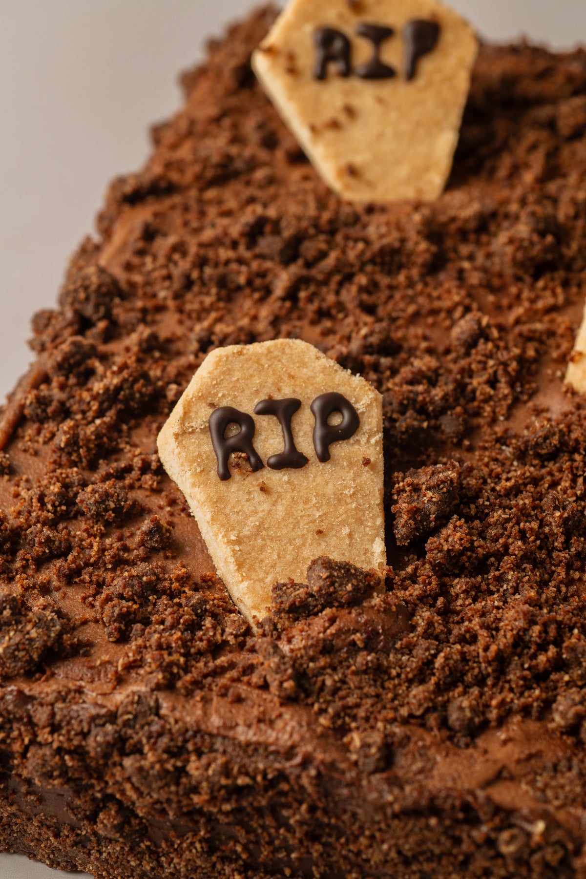 Tarta de Halloween sin gluten y sin lactosa de NICOLINA Madrid, vista en tres cuartos con decoración de lápidas RIP y cobertura de chocolate.