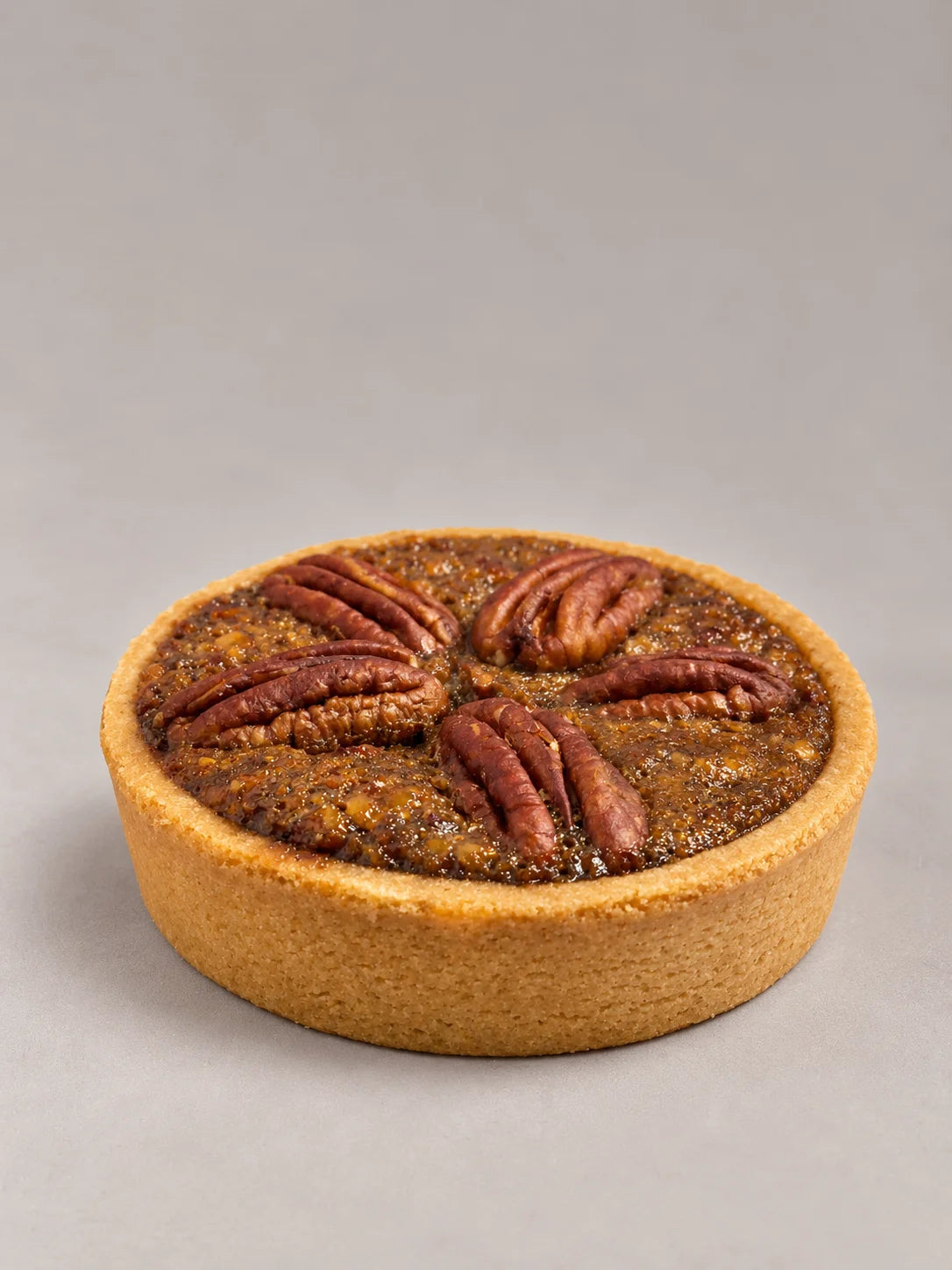 Pecan Pie artesanal sin gluten y sin lactosa, cortada por la mitad, con relleno de nueces pecanas y caramelo sobre base crujiente.
