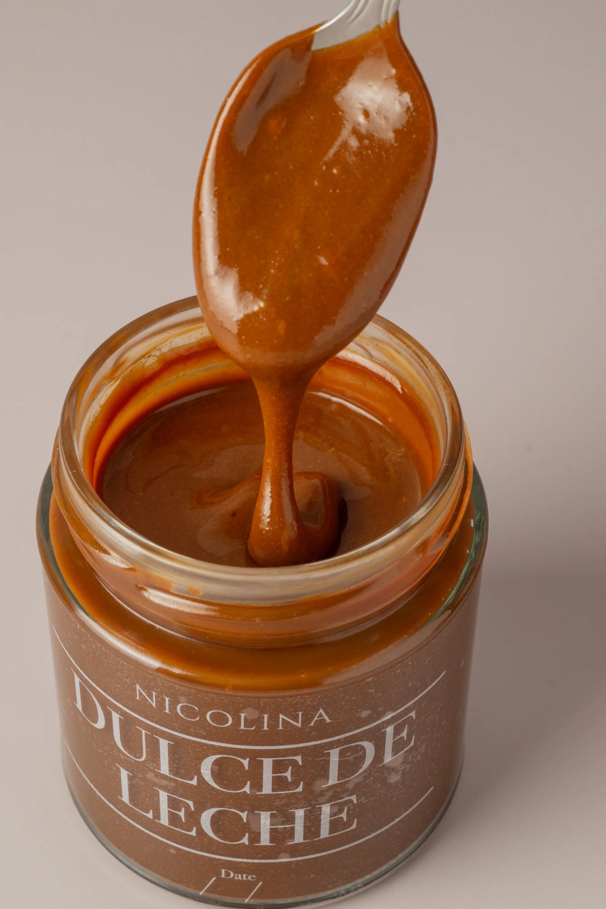 Dulce de leche sin gluten, sin azúcar y sin lactosa servido en cuchara mostrando su textura suave y cremosa.
